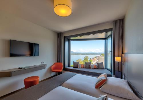 a hotel room with a bed and a large window at Lake Geneva Hotel in Versoix