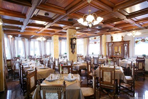 ヴェレニエにあるHotel Razgorsekのテーブルと椅子、シャンデリアのあるレストラン