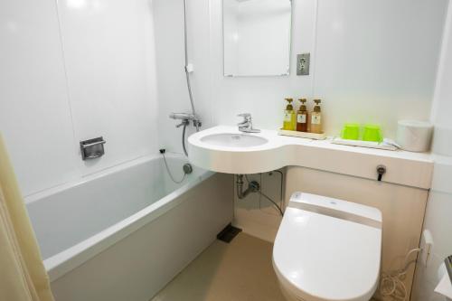 a bathroom with a toilet and a sink and a bath tub at Green Hill Hotel Urban in Kobe
