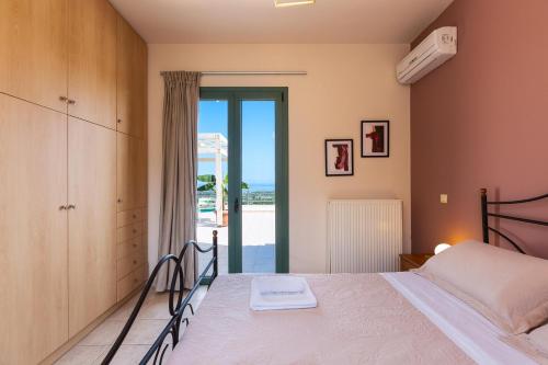 ein Schlafzimmer mit einem Bett und einem Balkon in der Unterkunft Archos Villa with Pool, Play Area,BBQ & Amazing View!! in Mési