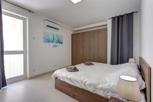 a bedroom with a bed and a large window at Harmony Apartments in Msida