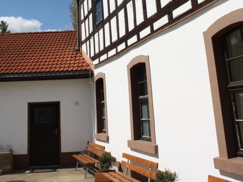 a white building with benches and a black door at Zu den grauen Ziegenböcken in Serba