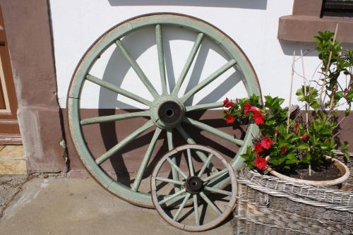 a green wagon wheel next to two baskets of flowers at Zu den grauen Ziegenböcken in Serba