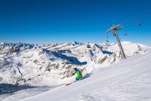 a person skiing down a snow covered mountain with a ski lift at Hotel Flattacher Hof in Flattach