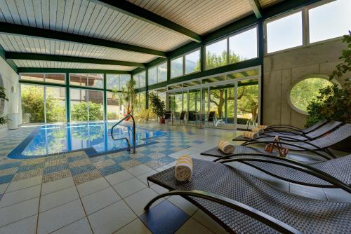 una piscina in un edificio con sedie e un barman di Hotel Flattacher Hof a Flattach