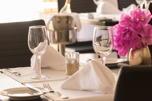 a table with two wine glasses and a vase with pink flowers at Agua Hotels Sal Vila Verde in Santa Maria
