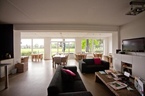 a living room with a couch and a dining room at De Slaapfabriek vakantiehuis en trainingslocatie in Teuge