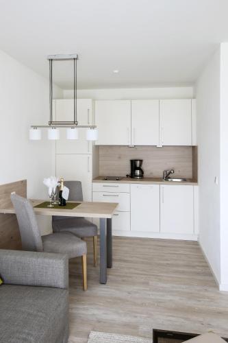 a kitchen with white cabinets and a table and chairs at Appartementhotel Fidelio in Bad Füssing