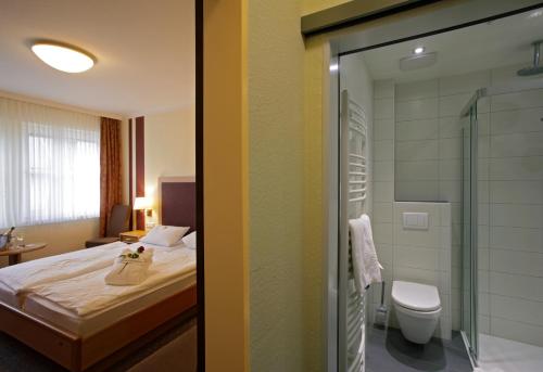 a bedroom with a bed and a shower and a toilet at Landhotel Hermannshöhe in Legden