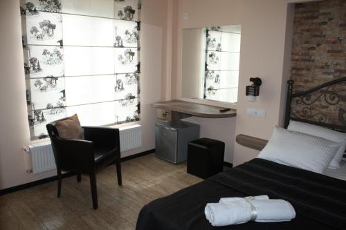 a bedroom with a bed and a desk and two windows at Hotel Delisi in Tbilisi City