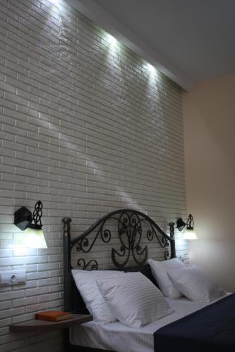 a bed with two lights on a brick wall at Hotel Delisi in Tbilisi City