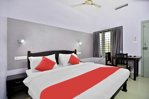 a bedroom with a large bed with red and white pillows at Shanthi Residency in Pathanāmthitta