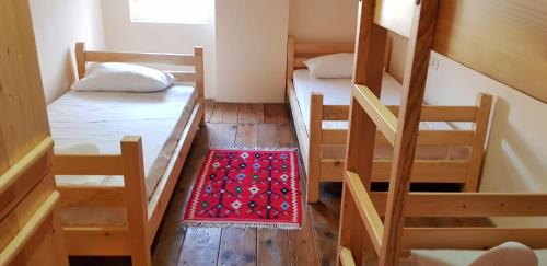 a small room with two bunk beds and a red rug at Teo’s Guest House in Berat