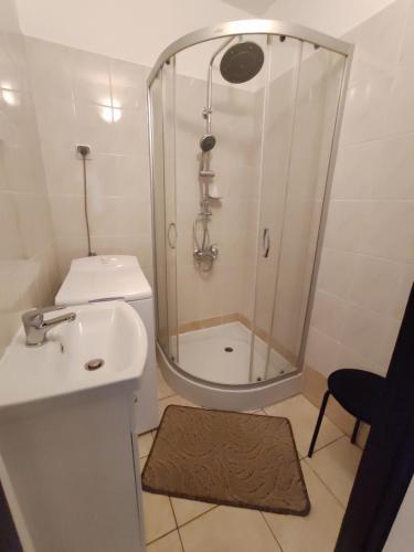 a white bathroom with a shower and a sink at Mieszkanie z dobrą energią in Giżycko