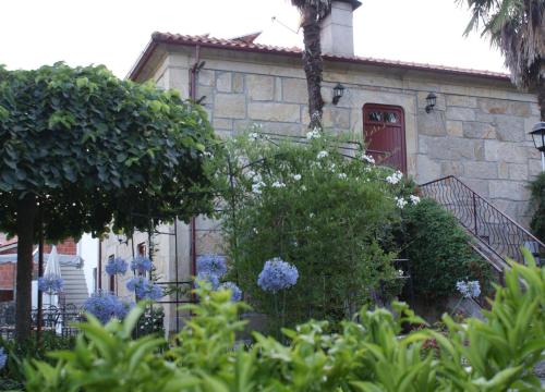 a stone house with a red door and some bushes at Quinta de Canhões in São Pedro do Sul