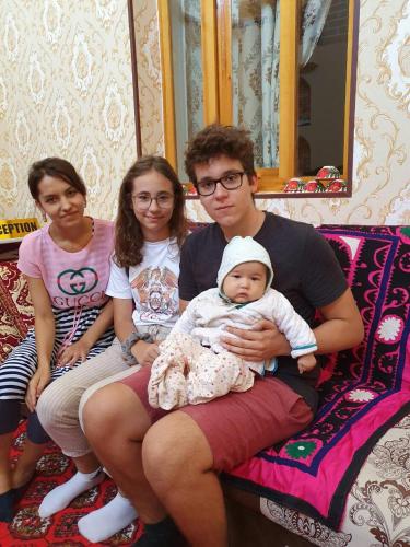 a family sitting on a couch holding a baby at Khiva Ibrohim Guest House in Khiva