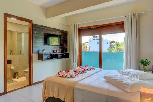 a bedroom with a large white bed with a balcony at i9 Quixaba Flat in Itacaré