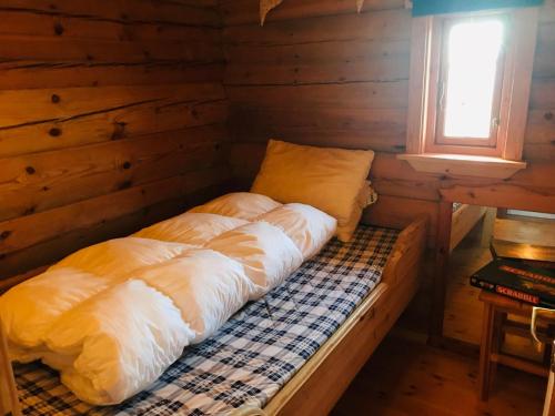 łóżko w drewnianym domku z oknem w obiekcie Midnight Sun Lodge Lofoten w mieście Bøstad