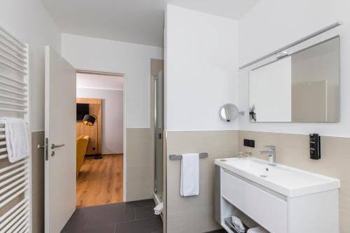 La salle de bains est pourvue d'un lavabo et d'un miroir. dans l'établissement mk hotel eschborn, à Eschborn
