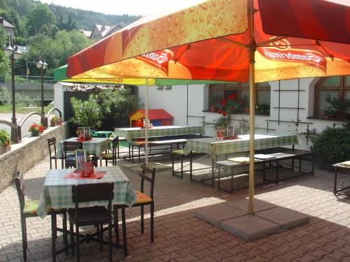 a patio with tables and chairs and an umbrella at Penzion Měšťanský Dům in Svoboda nad Úpou