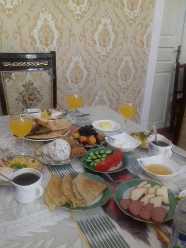 a table with plates of food and glasses of orange juice at Khiva Ibrohim Guest House in Khiva