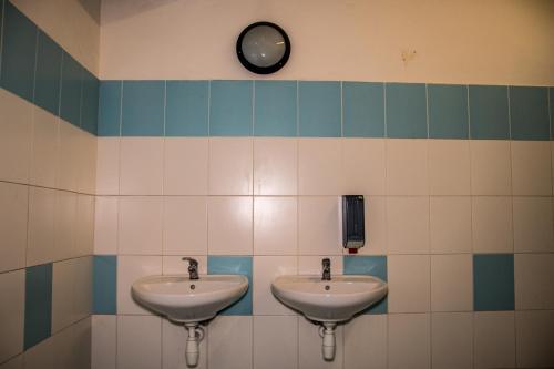 a bathroom with two sinks and a clock on the wall at Budget Hostel in Prague