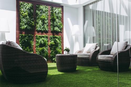 a patio with wicker chairs on a green lawn at Masa Hotel 5 de Outubro in Lisbon