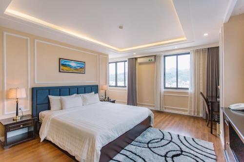 a bedroom with a large bed and a desk and windows at Cao Minh Hotel in Lao Cai