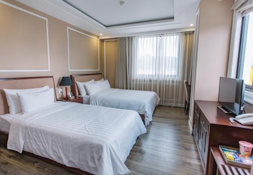 a hotel room with two beds and a television at Cao Minh Hotel in Lao Cai