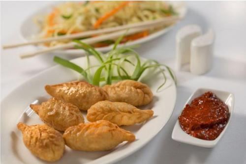 a plate of food with dumplings and sauce on a table at The Grand Dragon Ladakh in Leh