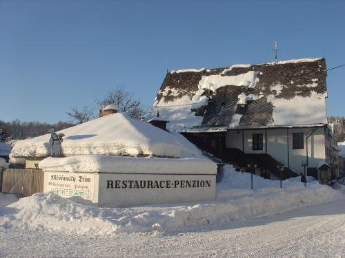 a house covered in snow in front of a house at Penzion Měšťanský Dům in Svoboda nad Úpou