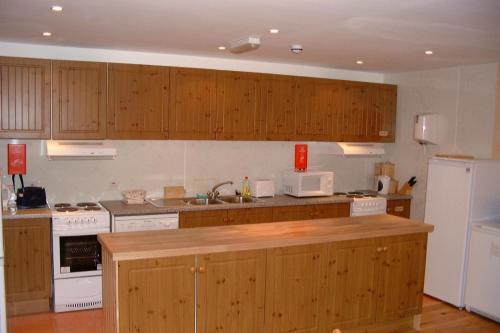 a kitchen with wooden cabinets and a white appliances at Sandras Backpackers in Thurso
