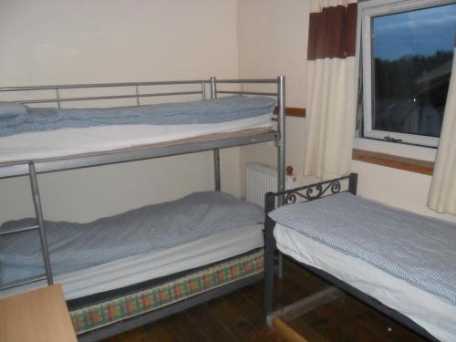 two bunk beds in a room with a window at Sandras Backpackers in Thurso