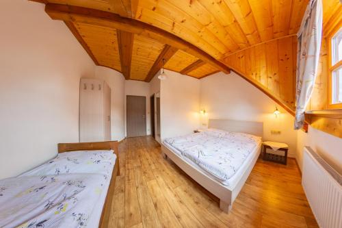 2 camas en una habitación con techo de madera en Pension & Restaurant U Koňské dráhy Holkov en Velešín