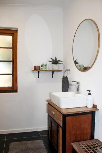 a bathroom with a sink and a mirror at Langbaai Beach Cottage in Hermanus