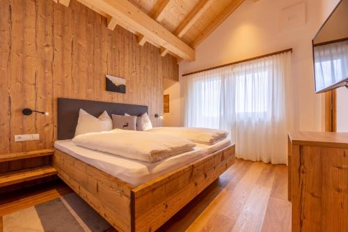 a bedroom with a large bed with a wooden wall at Reidenhof in Sesto