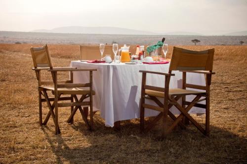 einen Tisch mit einem weißen Tischtuch und zwei Stühlen in der Unterkunft Saruni Eagle View in Naboisho