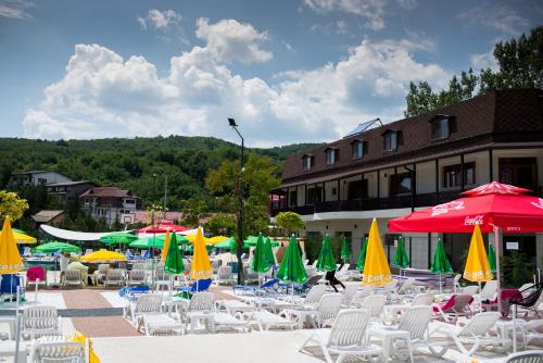 a group of chairs and umbrellas in front of a building at Pensiunea Duet in Sărata-Monteoru