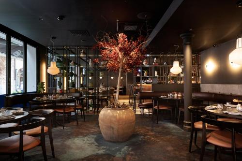 a restaurant with tables and chairs and a large tree in the middle at Elite Hotel Esplanade in Malmö