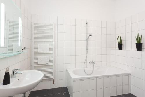 une salle de bain blanche avec un lavabo et une douche dans l'établissement The Cloud, à Berlin
