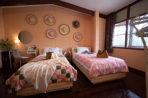 a bedroom with two beds and a window at Dunah's Garden Home in Bangkok
