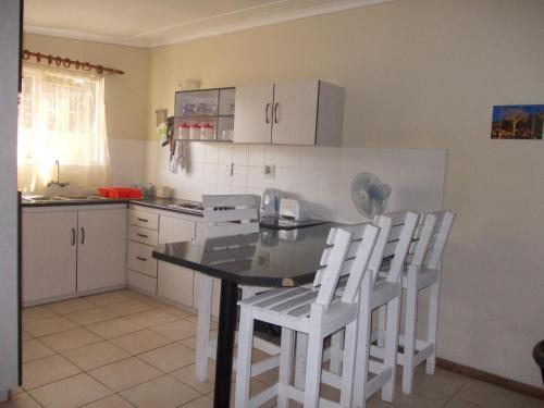 a kitchen with a table and two white chairs at Huis KlipdriftSelf Catering &B&B in Hentiesbaai