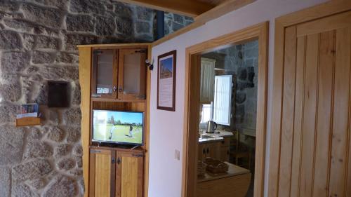 a room with a television in a stone wall at Casas da Villa- Monsanto in Monsanto
