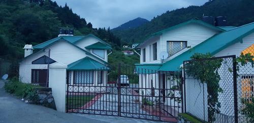 a white house with a gate with a mountain at Karinya Villas in Nainital
