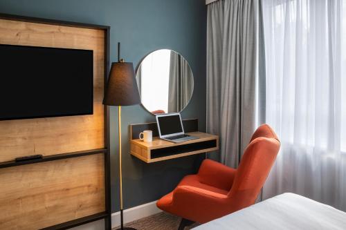 a hotel room with a bed and a chair and a mirror at Mercure Birmingham West Hotel in West Bromwich