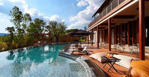 Una piscina con sillas y sombrilla al lado de un edificio. en Boribot Pool Resort, en Mu Si