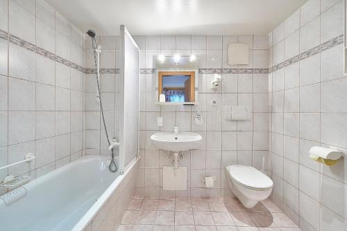 a bathroom with a sink and a toilet and a tub at Hotel Gasthof Schweizerhaus in Stuhlfelden