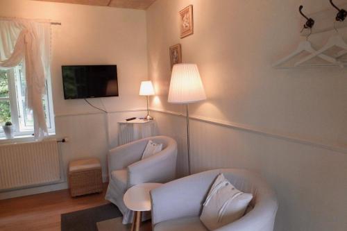 a living room with two chairs and a tv at Pension Lærkelill in Skovlund