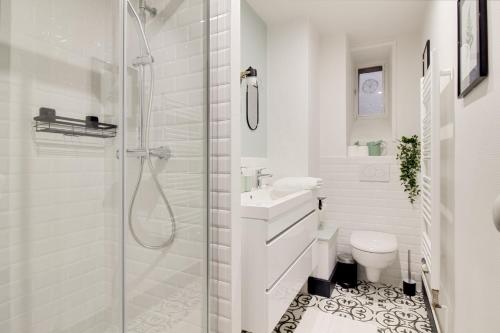 La salle de bains blanche est pourvue d'une douche et de toilettes. dans l'établissement Sous Le Cèdre - Au cœur de Nantes, à Nantes