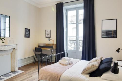 a bedroom with a bed and a window and a desk at Sous Le Cèdre - Au cœur de Nantes in Nantes